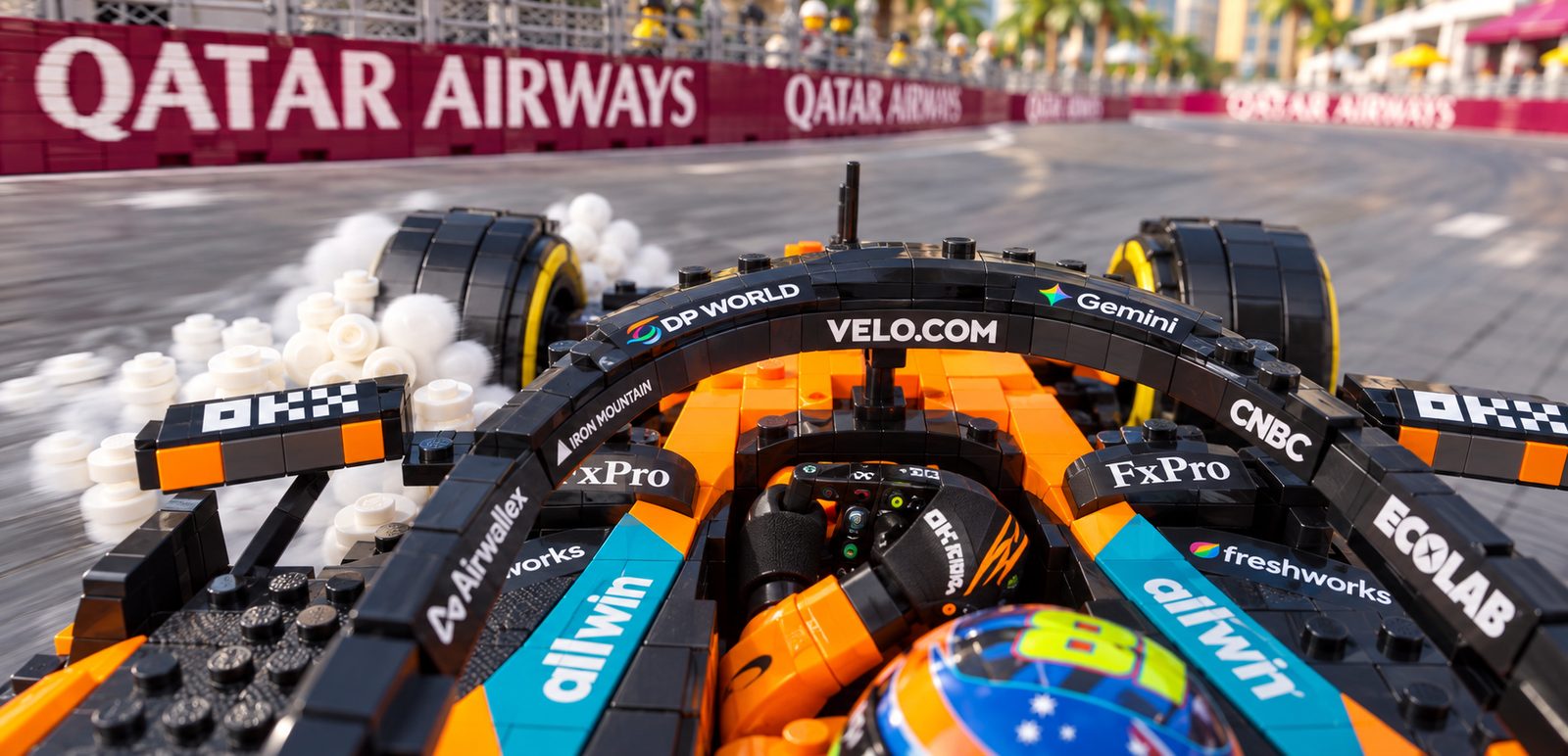 Cockpit view over the halo of Oscar Piastri's McLaren, the locked front tyre trailing smoke as the car runs wide at a corner lined with Qatar Airways boards.