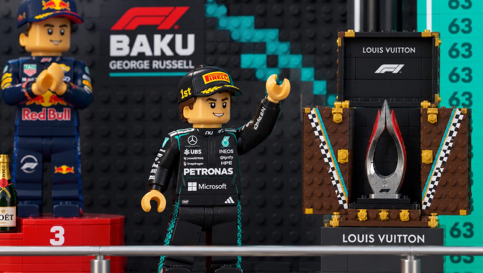 George Russell on the top step of the Baku podium in Mercedes overalls, waving, with the trophy beside him.